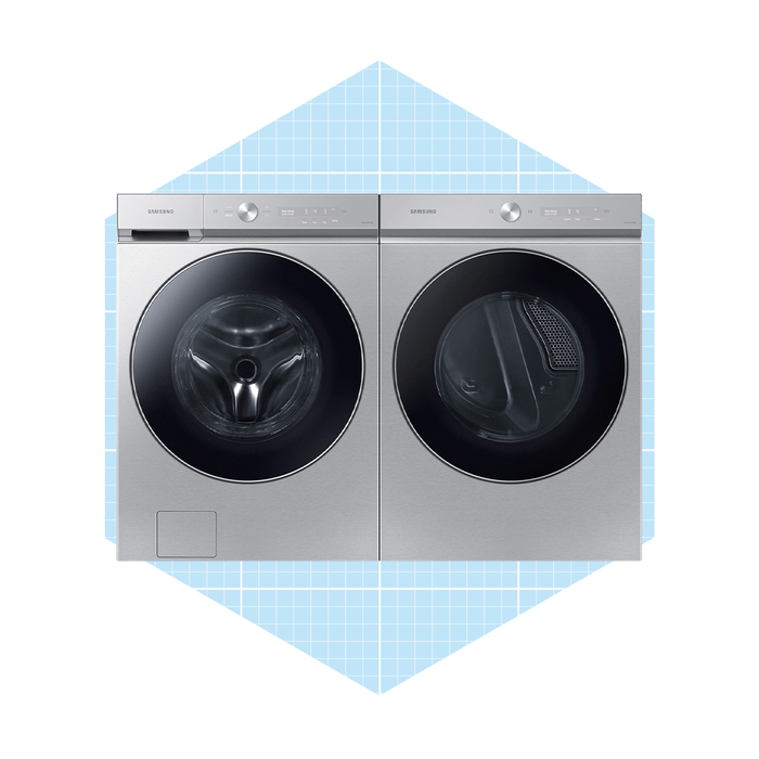 A stainless steel washer-dryer combo sits side by side, featuring transparent doors. They're placed against a light blue geometric background.