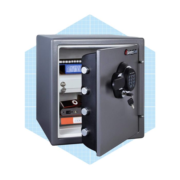 A gray safe stands open, displaying shelves with stacked items. It's equipped with a keypad and keyhole, set against a light grid background.
