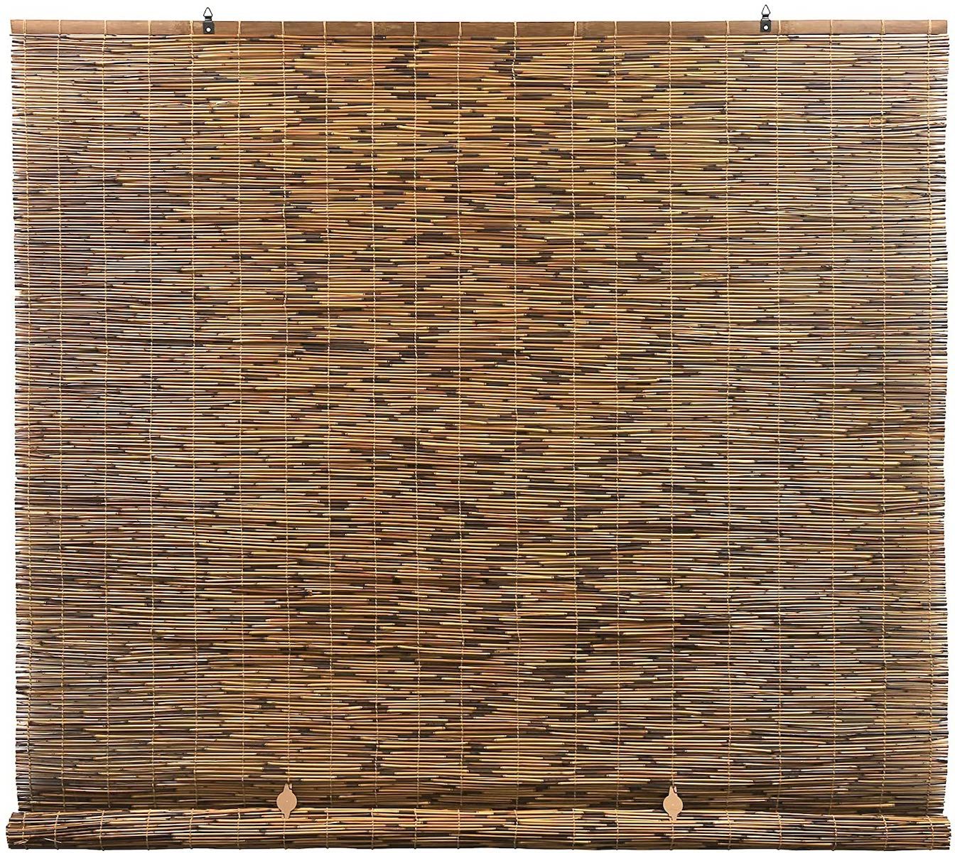 A bamboo window shade hangs vertically, filtering light in a room, offering a natural, textured appearance with alternating brown tones.