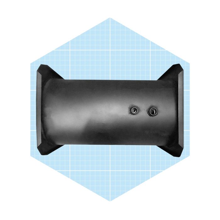 A cylindrical black object sits on a light blue grid-patterned background, featuring two openings near its center and flat edges for stability.