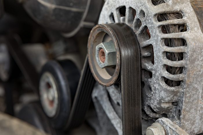A worn, old serpentine drive belt for motor on alternator pulley on automobile engine