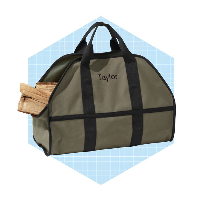 A green bag carries stacked firewood, positioned against a light blue checkered backdrop, suggesting use for outdoor or indoor activities involving fire.