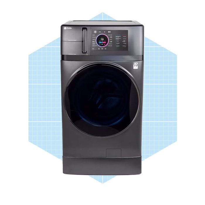 A black front-loading washing machine displays a digital control panel, with an open door, set against a light blue geometric background.