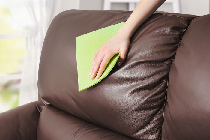 Leather sofa cleaning, woman's hand removes the dust with cloth from the firniture,clean the spot.