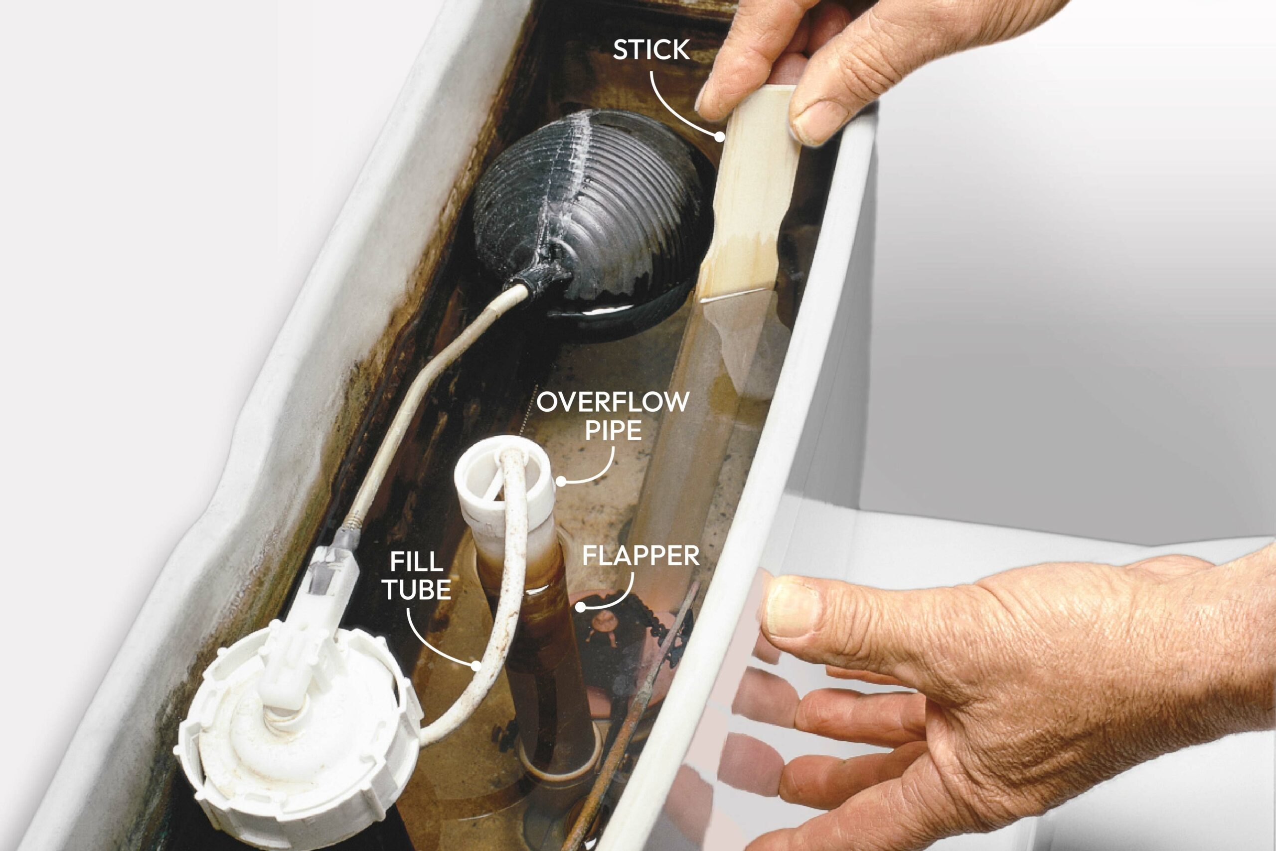 A hand is reaching into a toilet tank filled with water, adjusting components like a float and flapper in a bathroom setting.