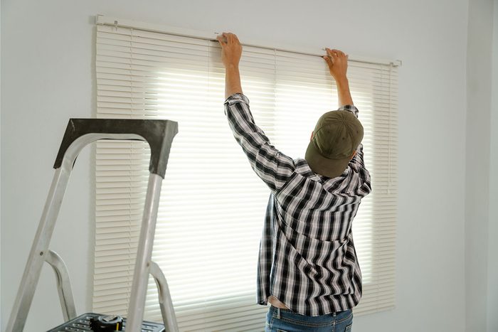 A professional blind installer adjusting sleek blinds in a modern house