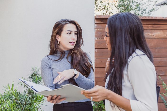 A female relator reviews documents with an interested homebuyer while showing a home