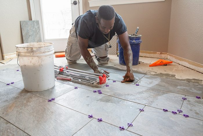 man installing floor tiles in kitchen