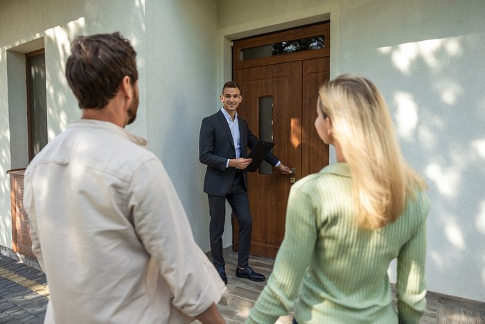 real estate agent opening door for couple