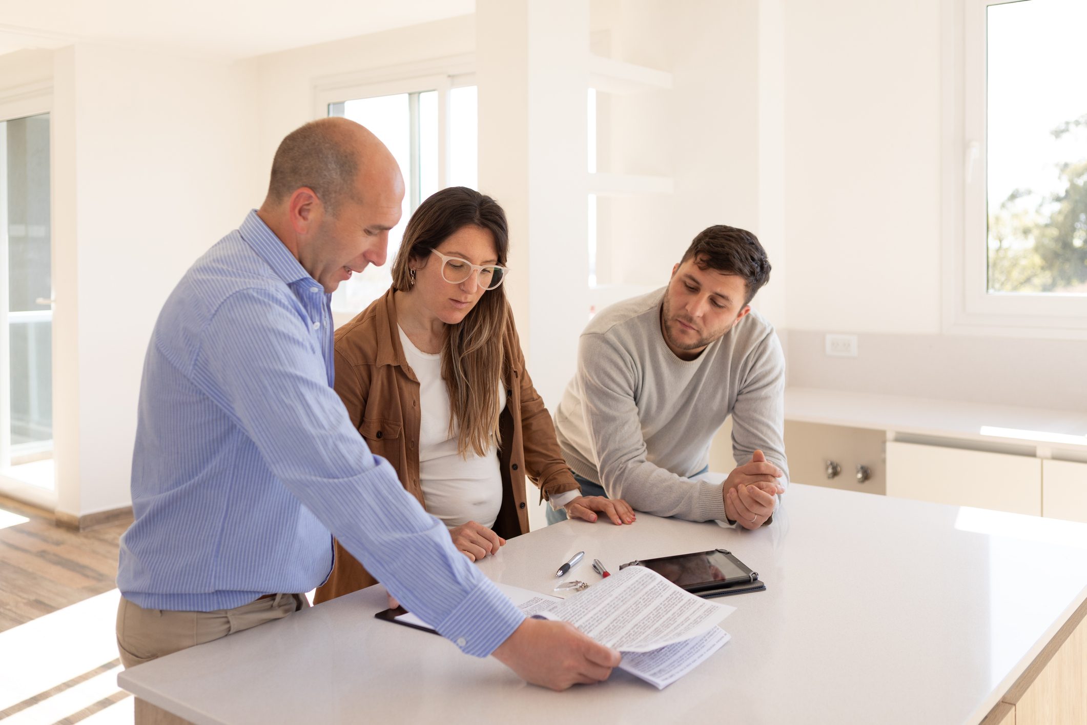 Real estate agent and young couple signing contract for their new home